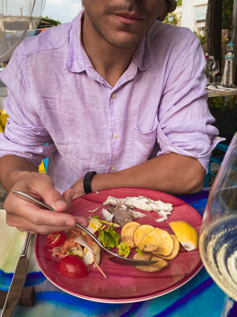 Fresh Italian seafood plate with tomatoes, lemon, and white wine at an outdoor restaurant in Anacapri