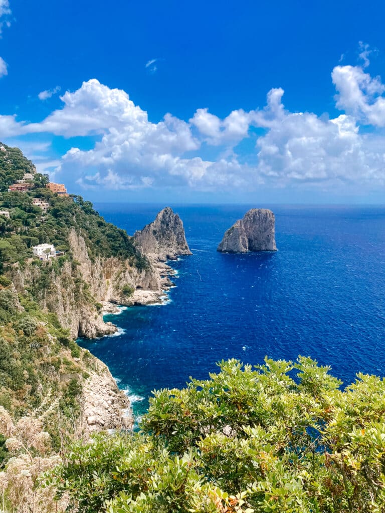 View of the Faraglioni sea stacks from the Giardini di Augusto with deep blue water and rocky cliffs