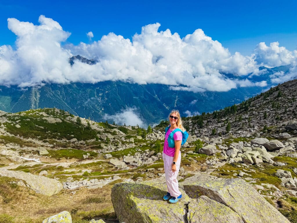 Female hiker standing on a granite boulder above the Chamonix valley with billowing summer clouds on the Grand Balcon Nord