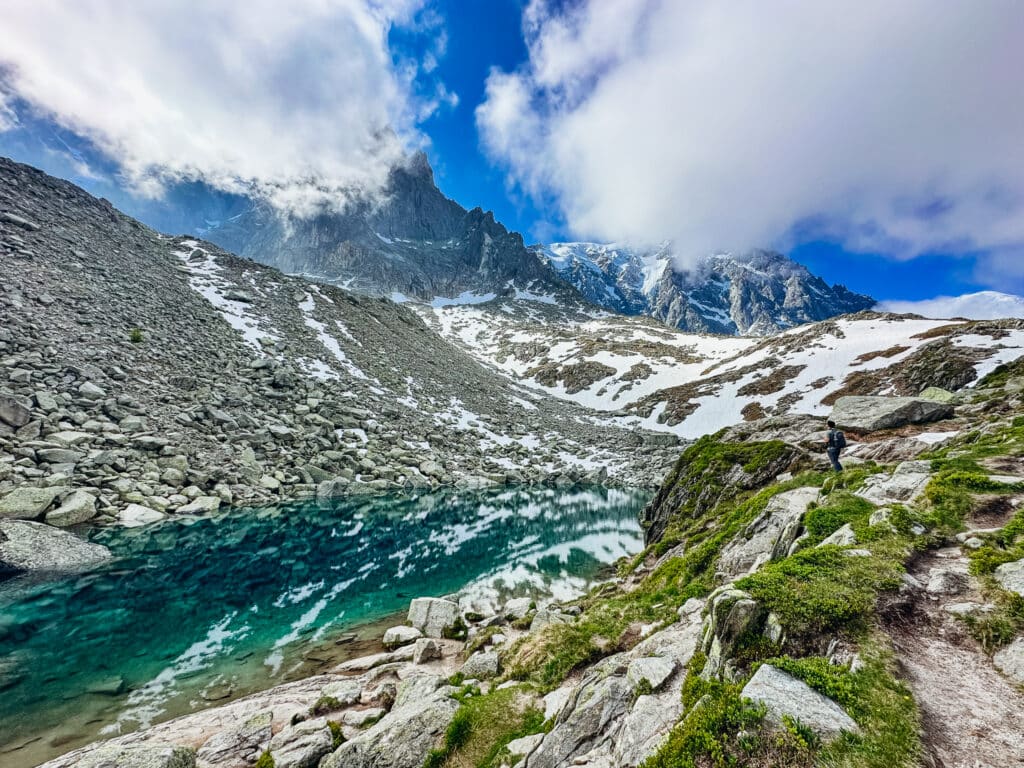 Turquoise glacial tarn reflecting the snow-streaked Aiguilles de Chamonix along the Grand Balcon Nord, French Alps