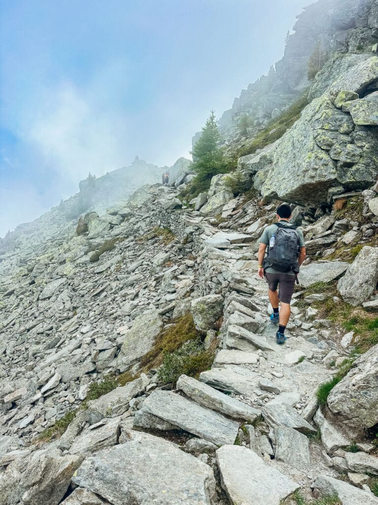 Hiker climbing the rugged stone-step ascent toward Signal Forbes on the Grand Balcon Nord, Chamonix