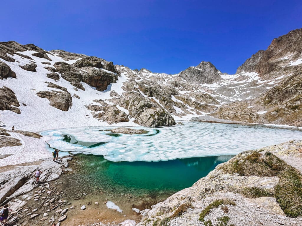 Partially frozen turquoise Lac Blanc surrounded by snow patches and rocky alpine ridges in the Aiguilles Rouges, Chamonix