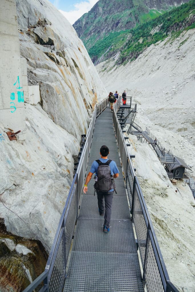 Hiker with backpack descending the long metal stairway leading down to the Mer de Glace ice cave
