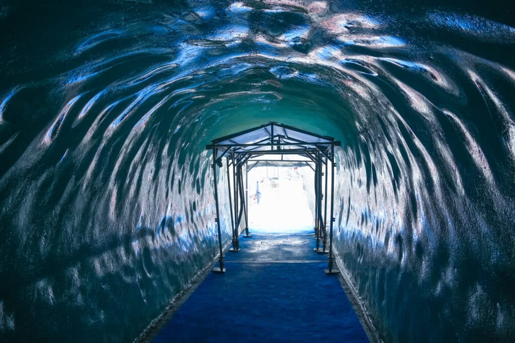 ooking out through the metal-arched tunnel exit of the Mer de Glace ice cave toward bright daylight