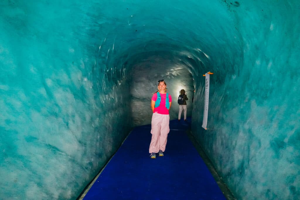 Woman in pink standing in the middle of the turquoise Mer de Glace ice cave tunnel in Chamonix