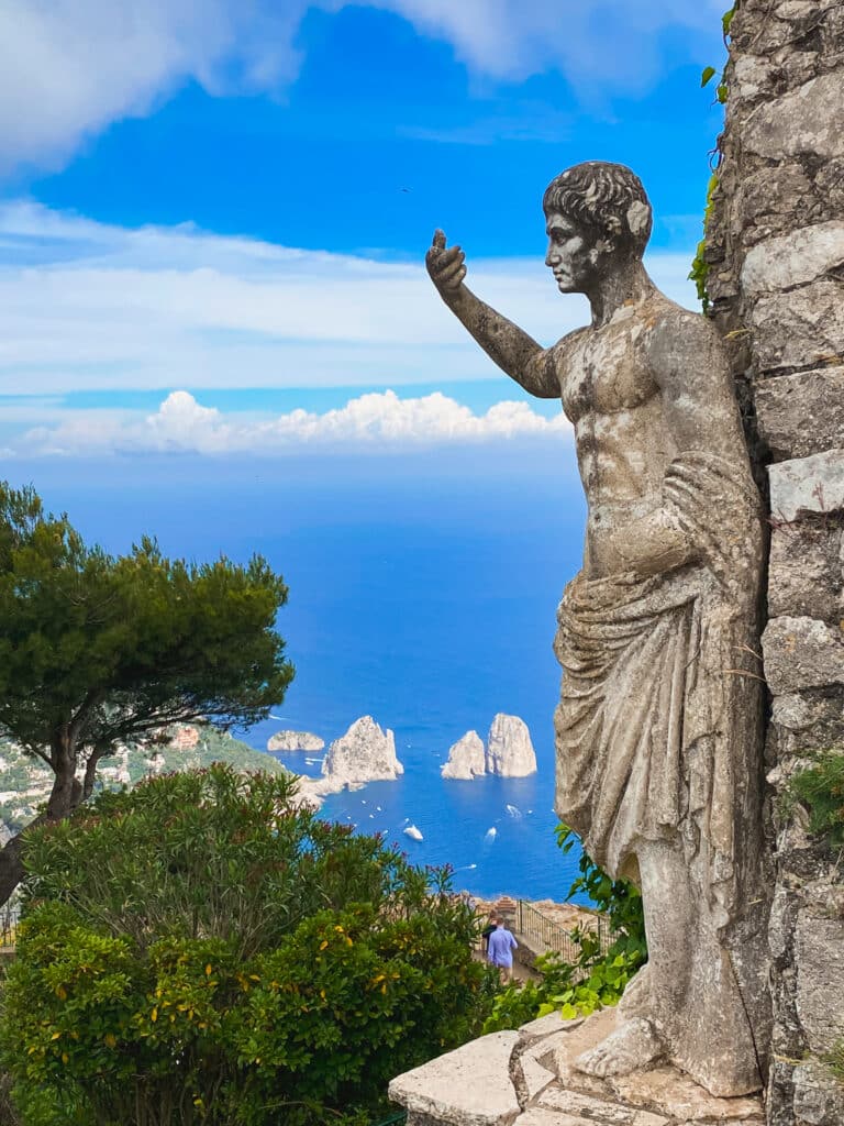 Close-up of the Roman statue at Monte Solaro with Faraglioni sea stacks and blue sky in the background