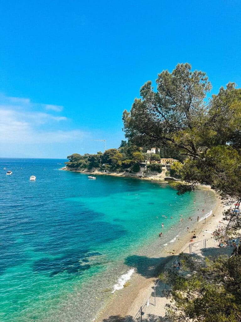 View of Paloma Beach cove with curved shoreline and trees along the coast and construction fencing