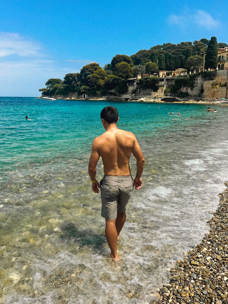 Person walking into the sea over pebbles at Paloma Beach in Cap Ferrat