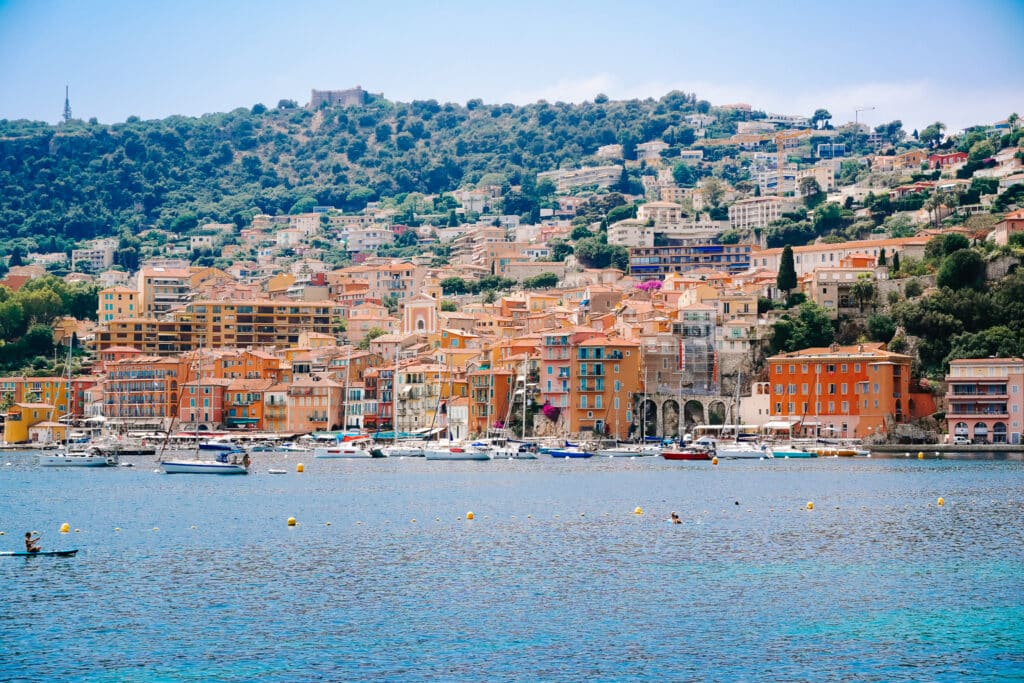 Orange and saffron colored houses rise above the bay of Villefranche-sur-Mer on a sunny summer's day