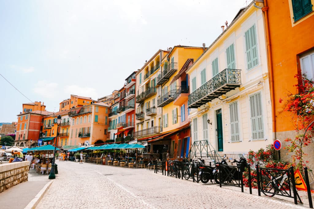 Orange and yellow pastel facades of the tightly clustered buildings facing the waterfront along the harbour in Villefranche-sur-Mer