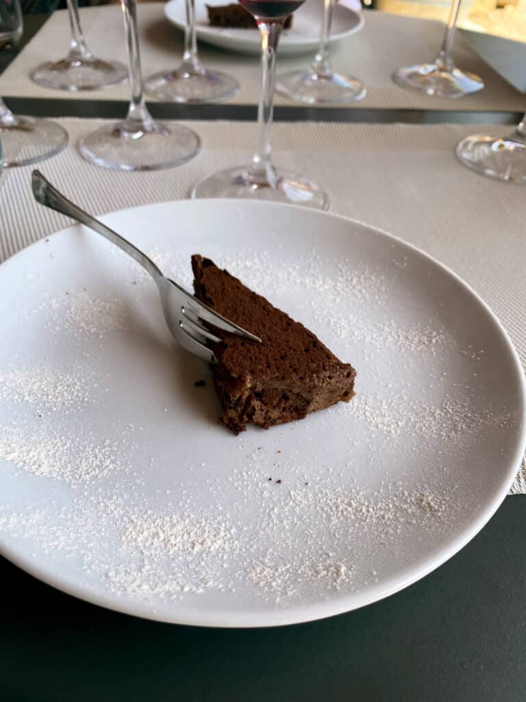 Slice of warm chocolate cake on a powdered-sugar-dusted plate, served as dessert during the wine tasting lunch at Agriturismo Marciano.