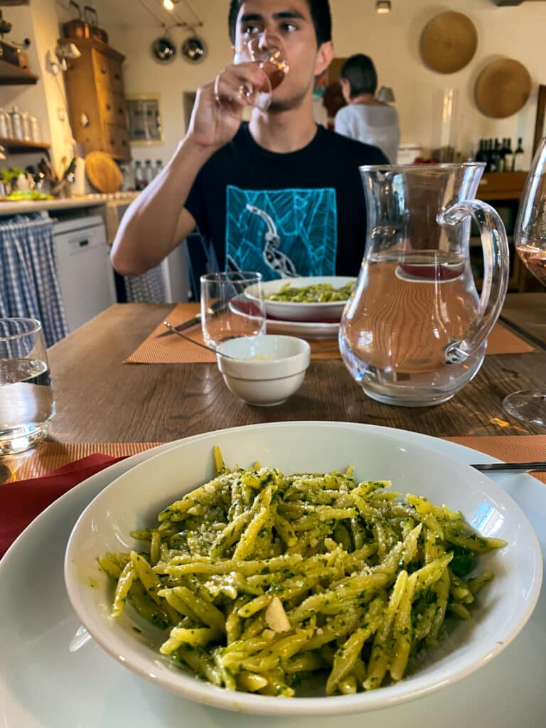 Dinner of homemade pesto pasta with a carafe of rosé wine in the shared kitchen at Agriturismo Marciano, Tuscany.