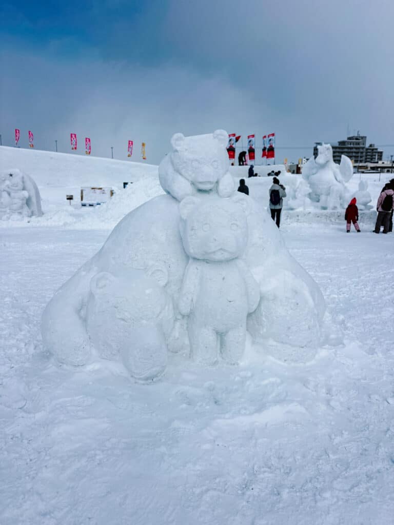 Trio of bear snow sculptures, including a teddy bear stacked on a larger bear, at Asahikawa Winter Festival in Hokkaido.