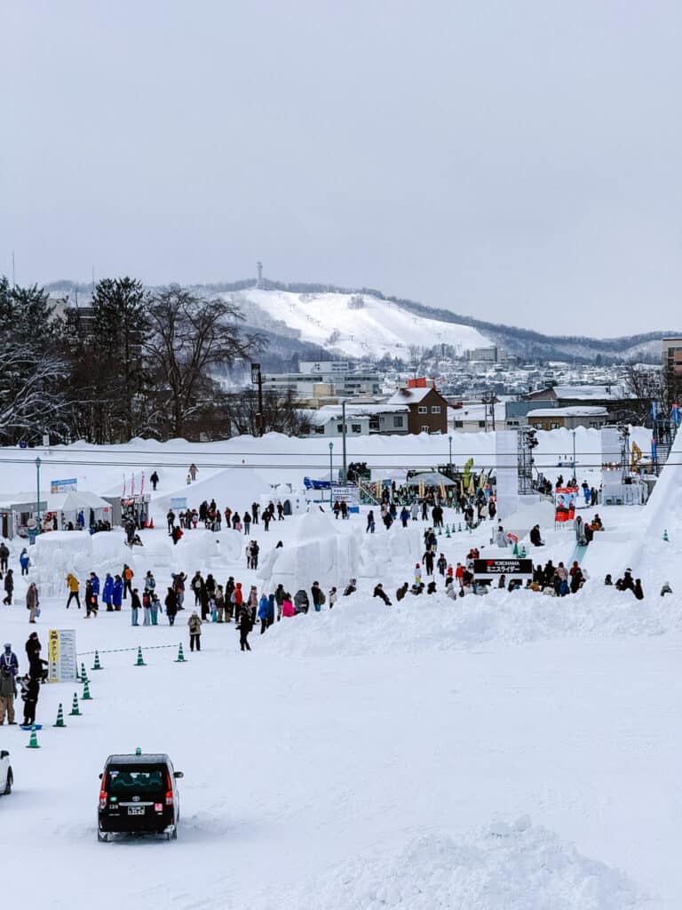 Wide view of the Asahikawa Winter Festival grounds with a snowy tubing hillside