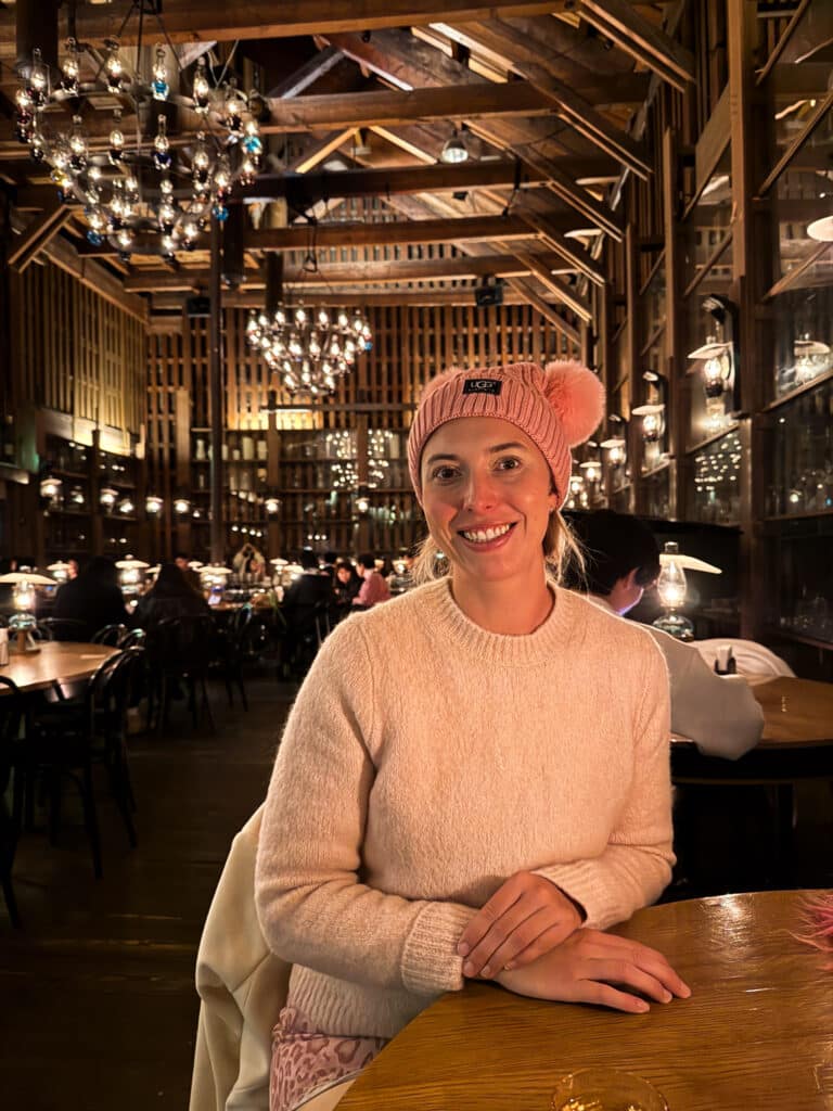 Woman in a pink pom pom hat seated beneath the kerosene-lamp chandeliers of Kitaichi Hall café in Otaru