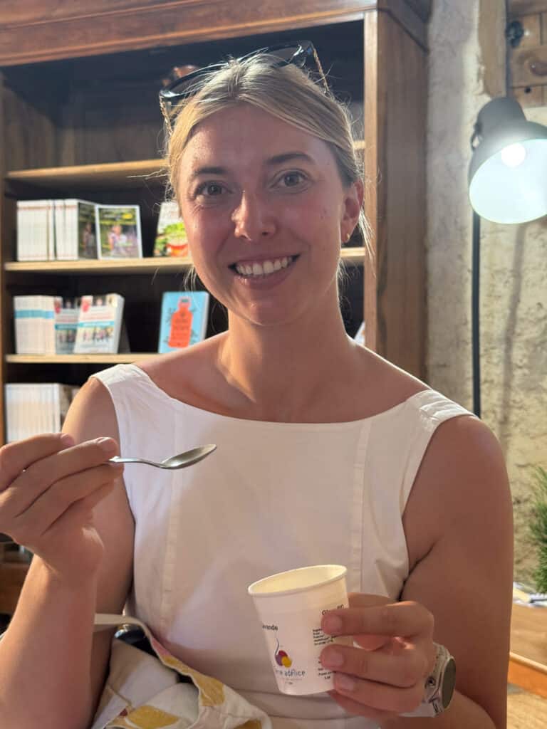 Woman tasting homemade lavender ice cream from a paper cup at a creamery in Sault, the lavender capital of Provence