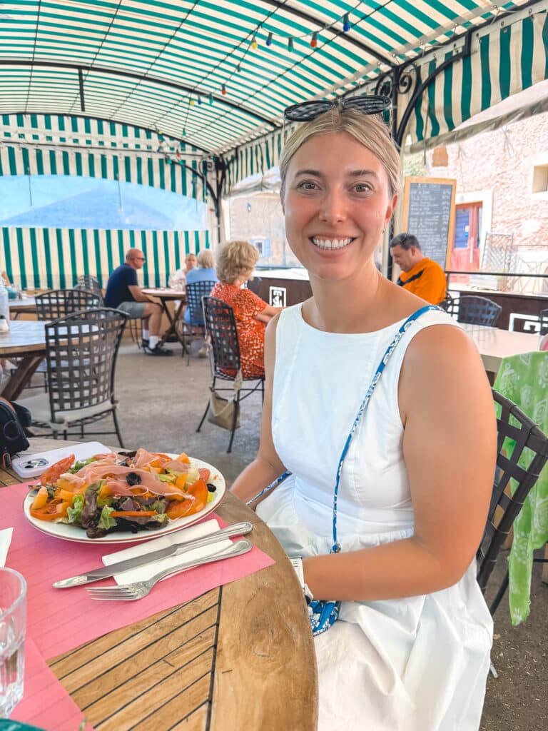 Woman enjoying a Provençal salad at an outdoor café terrace in Sault village during a lavender day trip