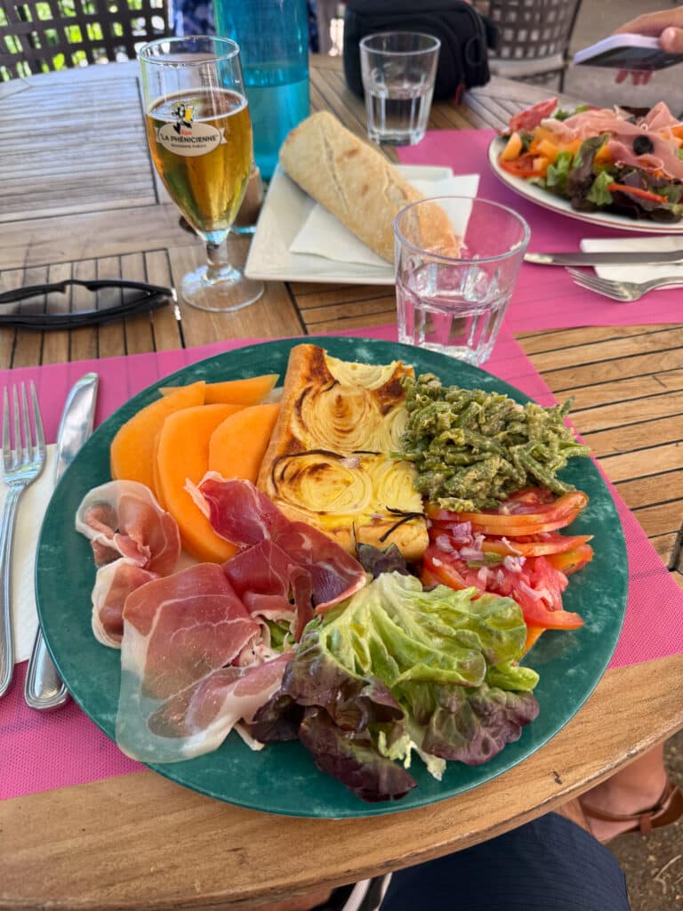 Provençal charcuterie plate with melon, tomato salad, beer and fresh baguette on a Sault café terrace