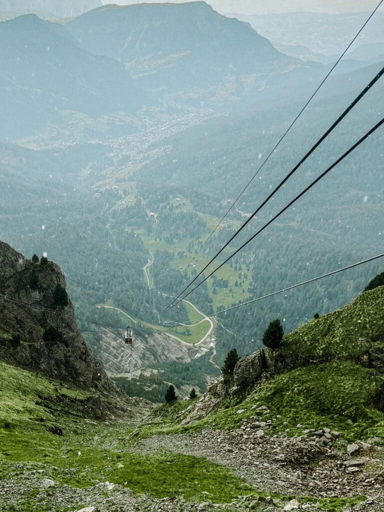 View from the Seceda cable car down the cables to the hazy green valley and village below, Dolomites, Italy