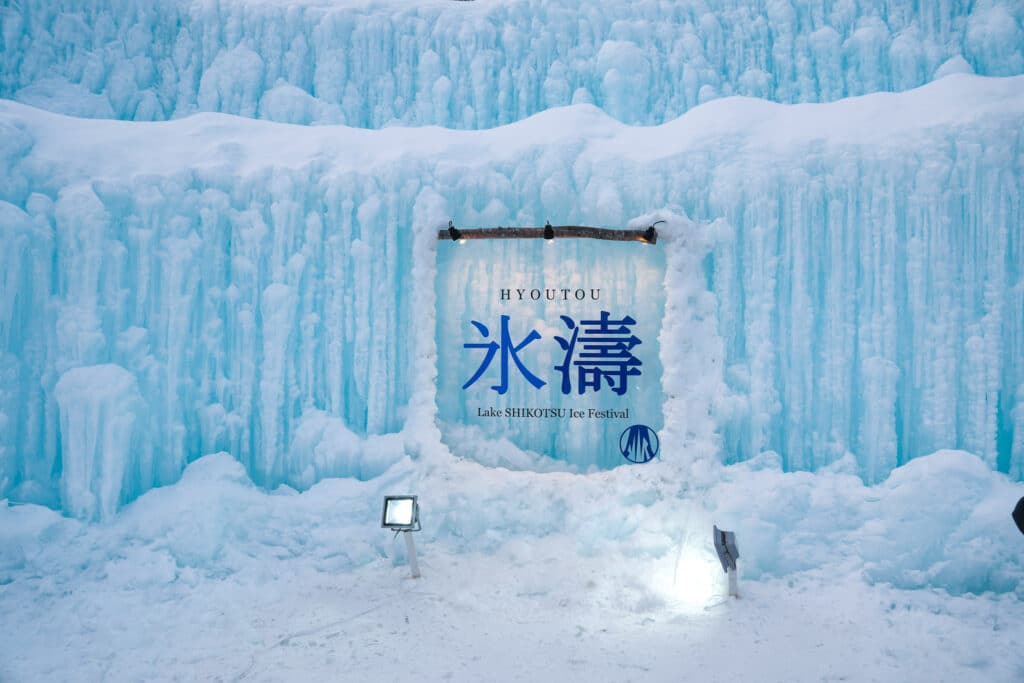 Lake SHIKOTSU Ice Festival entrance sign reading "Hyoutou" in blue Japanese kanji, framed by a wall of carved ice