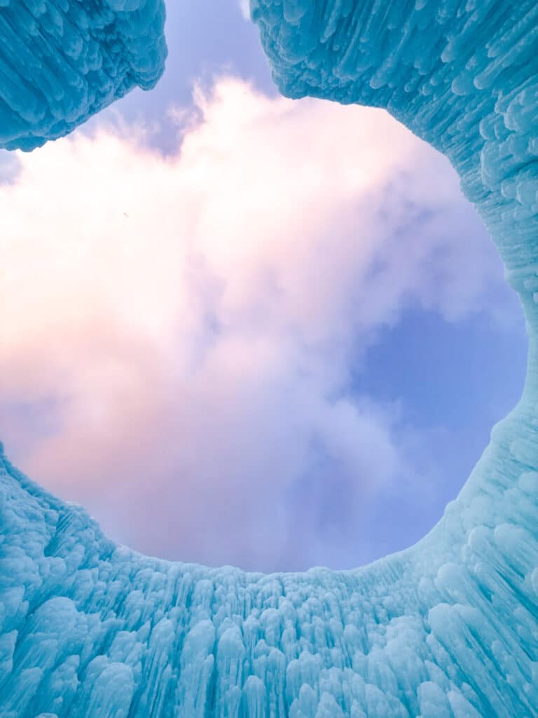 Pink and blue twilight sky framed by an oval opening in a sculpted ice tower at the Lake Shikotsu Ice Festival
