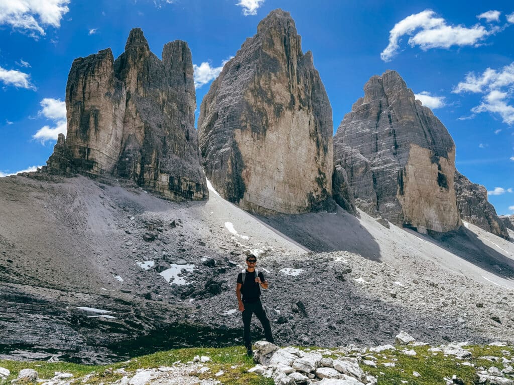 Male hiker posing at the base of the Tre Cime di Lavaredo north face on the loop trail in the Italian Dolomites