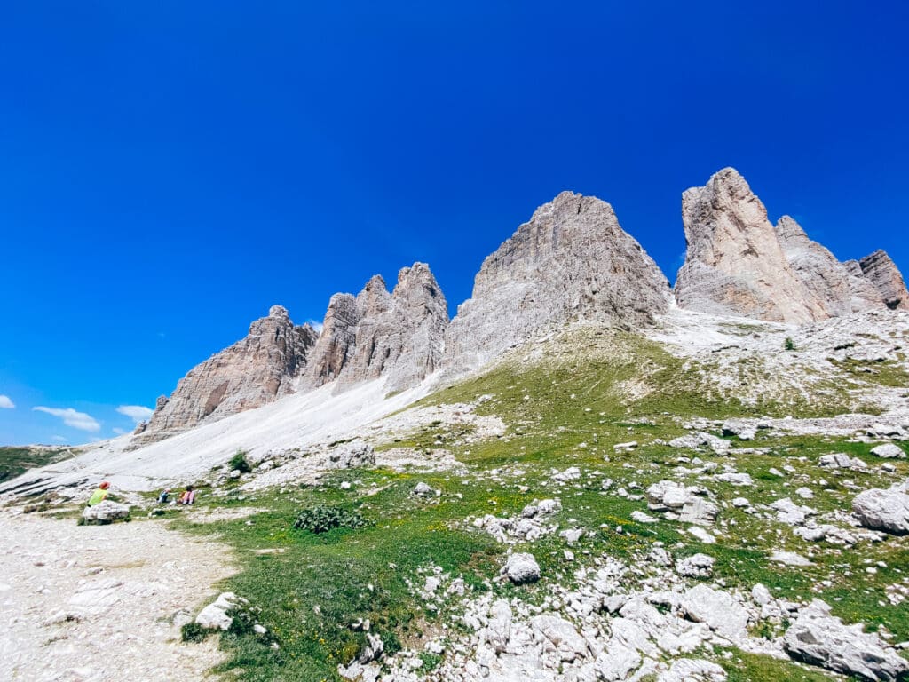 Wide side view of the Tre Cime di Lavaredo massif from a grassy meadow on the loop trail in summer