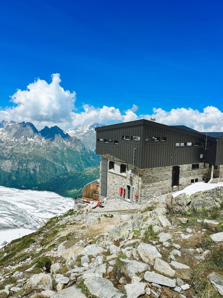 Modern Refuge Albert 1er building perched above the valley with peaks and clouds behind, Chamonix