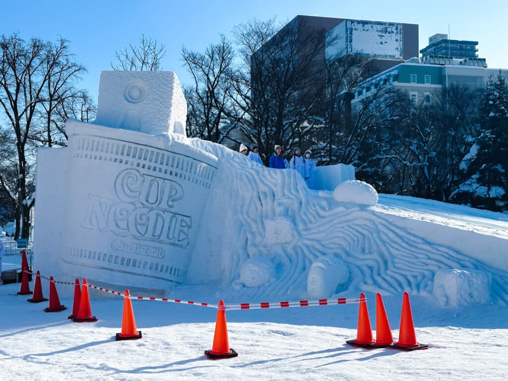 Cup Noodle-themed snow sculpture with swirling noodle details at Odori Park, Sapporo Snow Festival, Japan