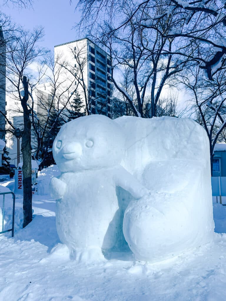 Chubby duck snow sculpture beside a high-rise at Odori Park during the Sapporo Snow Festival, Hokkaido, Japan
