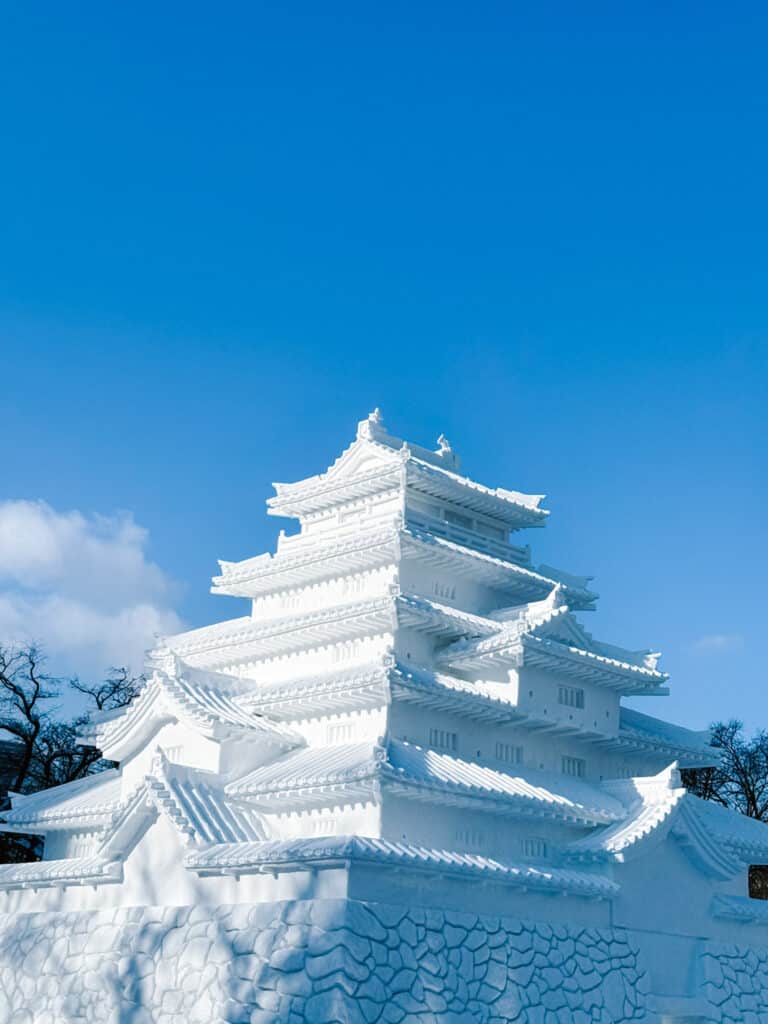 Multi-tiered Japanese snow castle rising against deep blue sky at the Sapporo Snow Festival, Hokkaido, Japan