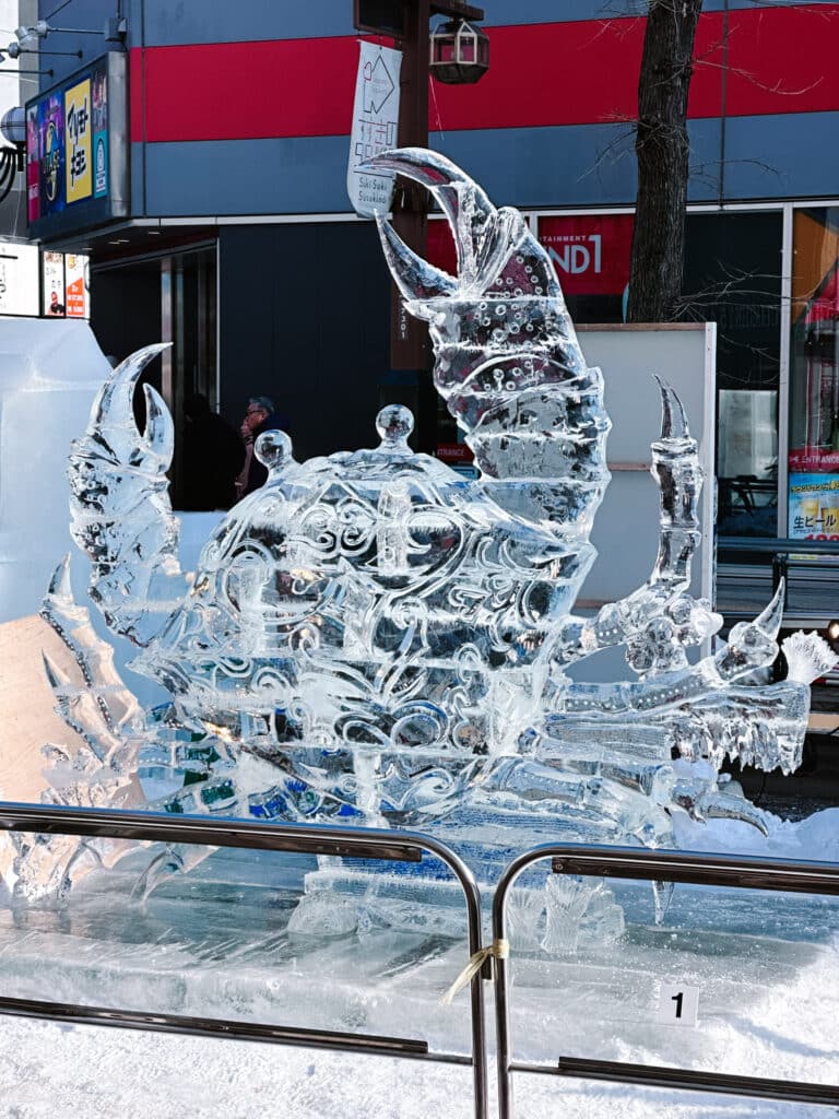 Clear ice sculpture of a crab carved with intricate detail in Susukino district, Sapporo Snow Festival, Hokkaido, Japan