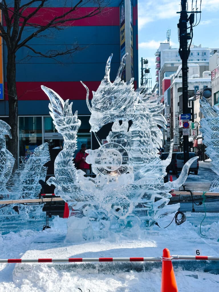 Detailed ice dragon sculpture glinting in daylight along Susukino's main street at the Sapporo Snow Festival, Japan
