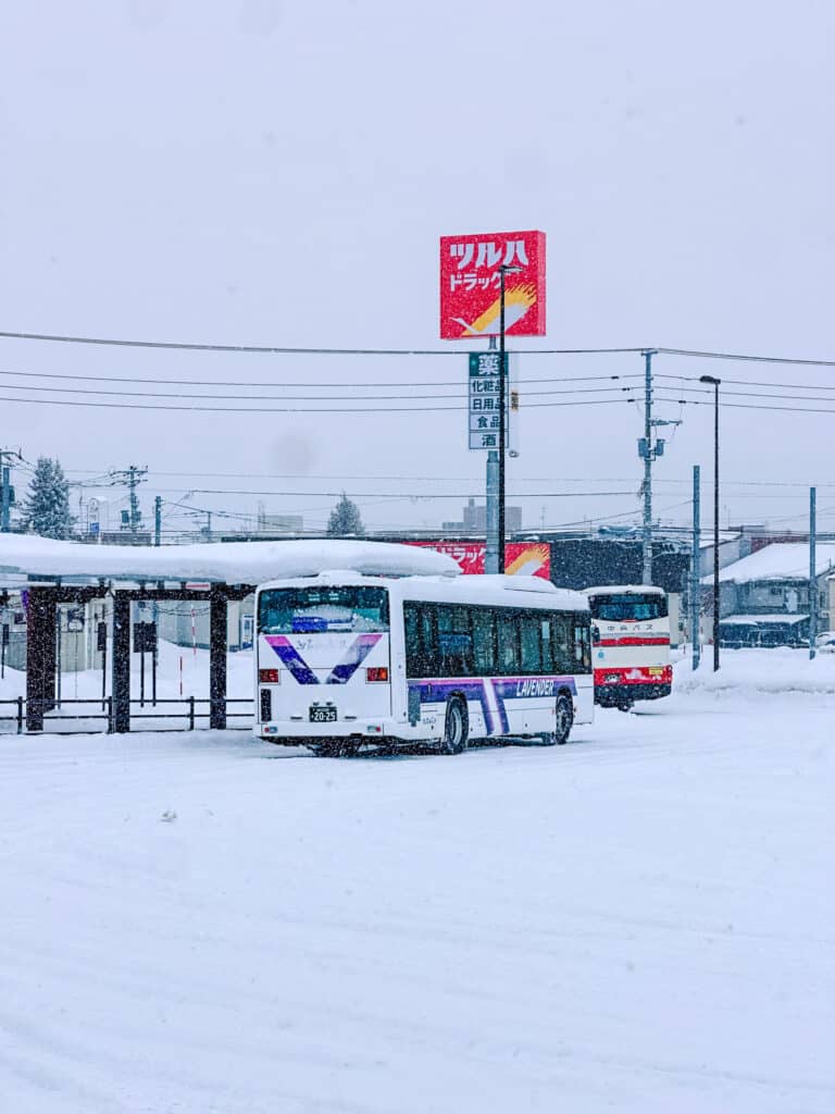 Furano Bus Lavender-liveried local bus and a Hokkaido Chuo Bus coach at the snowy Furano bus terminal, Japan